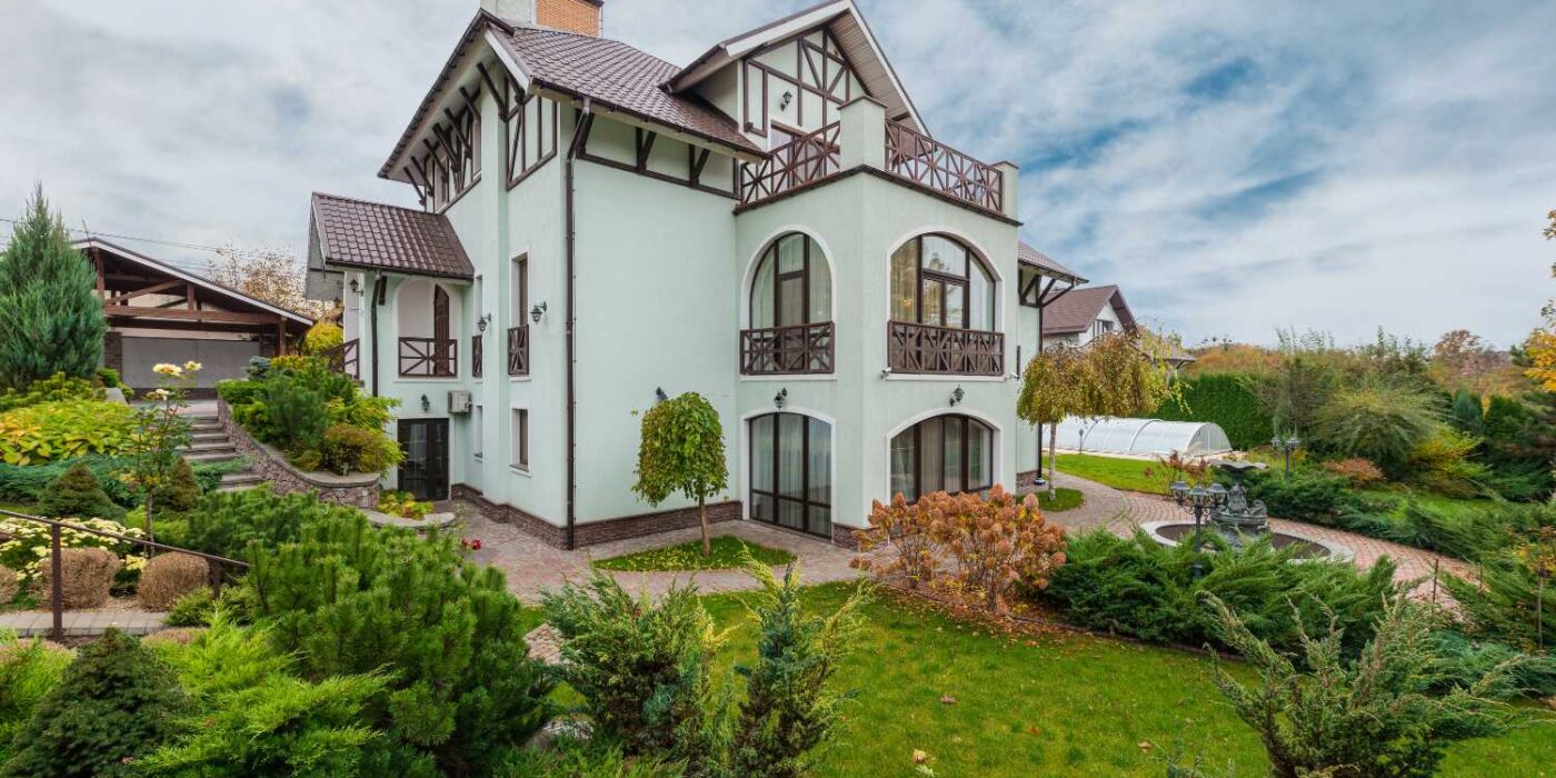 Luxury villa with landscaped garden, large windows, balconies, and a private outdoor area, showcasing upscale residential living in a peaceful suburban setting.